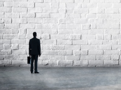 Photo showing a man standing at a brick wall, symbolizing therapy resistance indicators and a stalled psychotherapy journey.