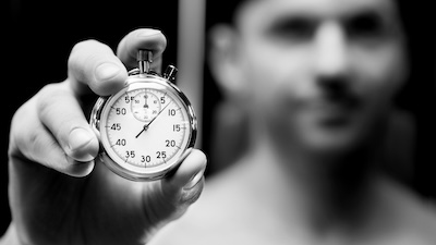 A close-up of a stopwatch held by a man, representing the therapeutic goal of increasing the pause between impulse and action.