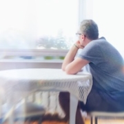 A man experiencing Prolonged Grief Disorder sitting by a window